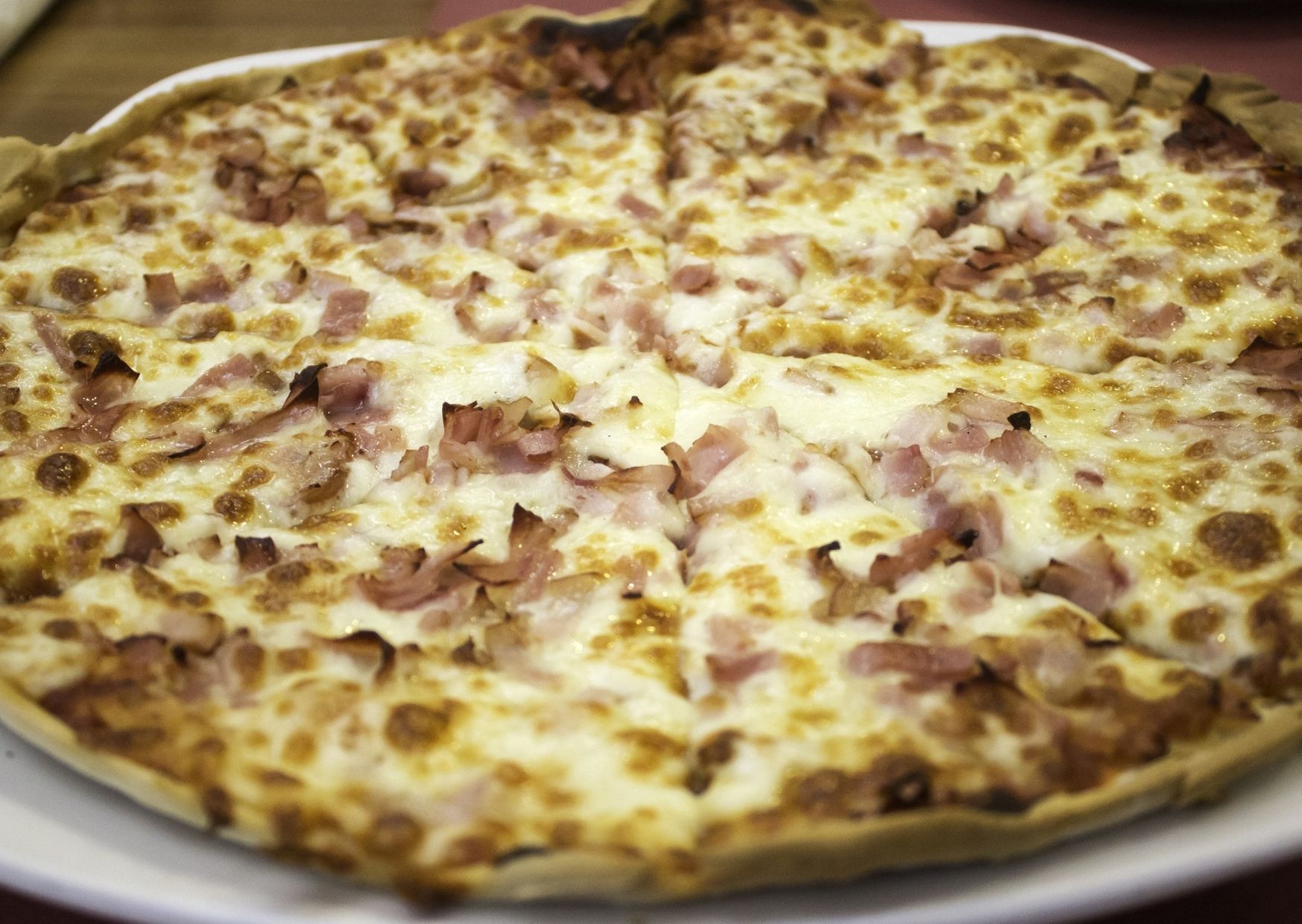 Pizza con panceta (bacón) tostada, salsa, cebolla y mozzarella